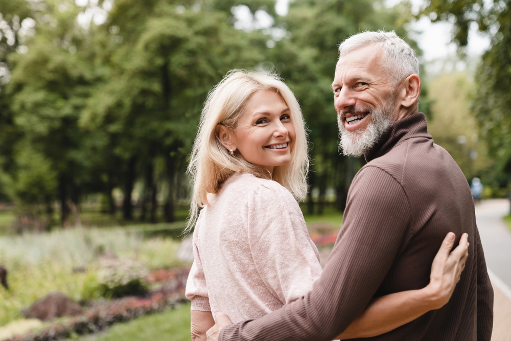 Senior couple smiling outdoors, representing long-term dental health and care with Pinhole Procedures