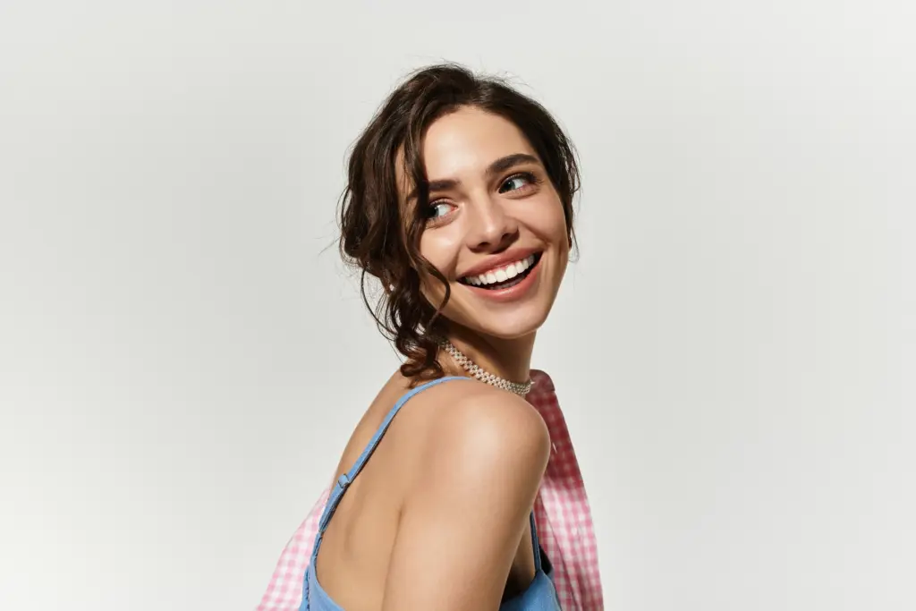 Smiling young woman with healthy teeth, representing confident smile after Pinhole Procedure