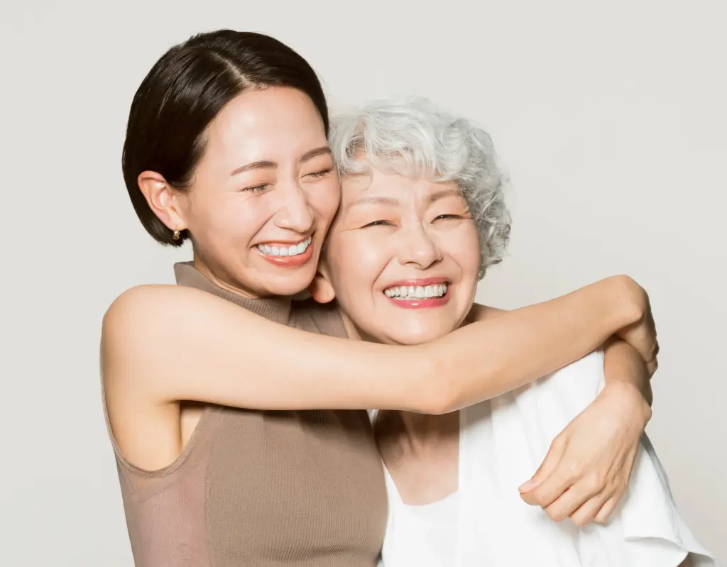 Young woman hugging elderly woman after dental implant, representing multi-generational dental care