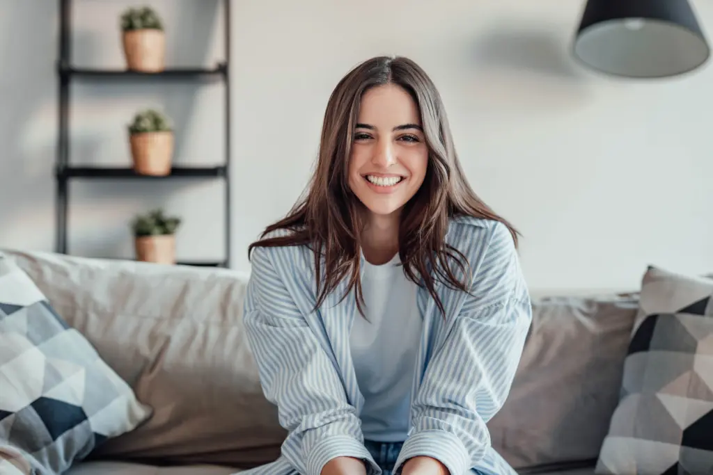 Smiling woman at home, representing comfortable and stress-free cosmetic dental care